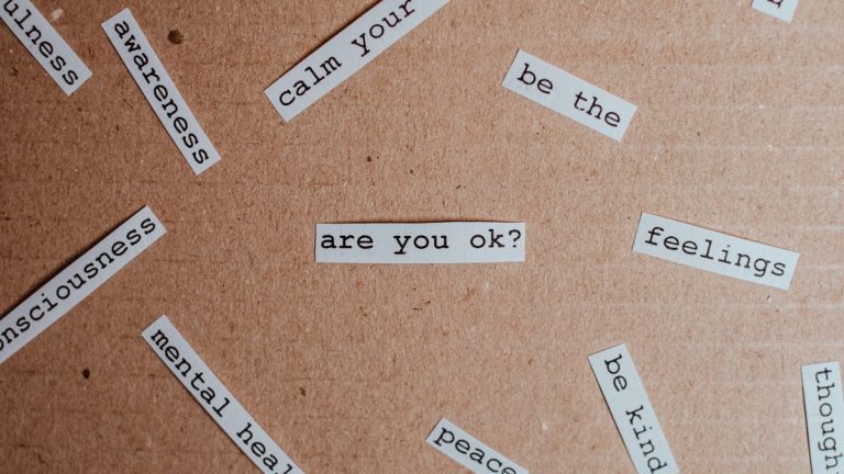 Cut-out words promoting mental health awareness on cardboard background.